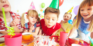 Group of adorable kids gathered around birthday cake with candles